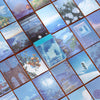 A close-up view of a sticker book featuring aesthetic landscape designs on square cards.