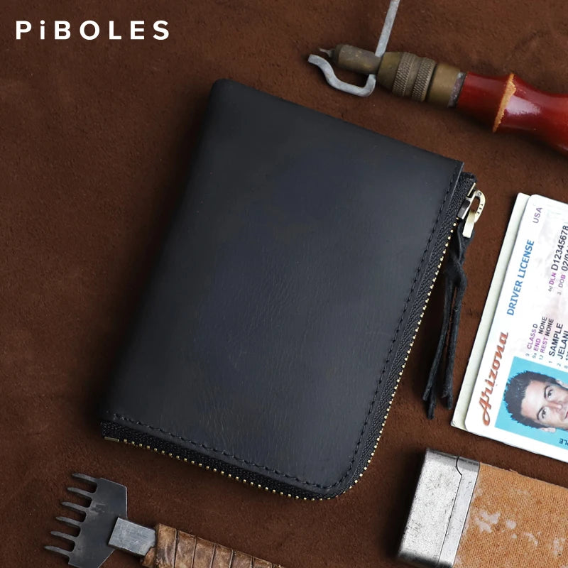 A black leather coin purse with a zipper is shown resting on brown fabric next to a knife and other leather items.