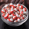 A bowl filled with small, round ceramic beads featuring a red and white floral pattern for jewelry making