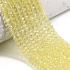 A close-up of a strand of faceted yellow crystal glass beads for jewelry making
