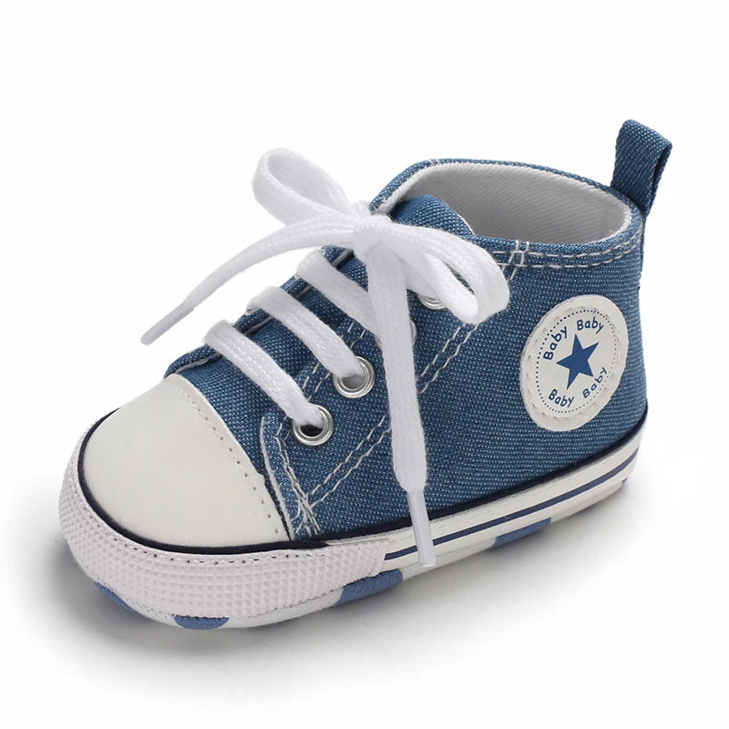 A pair of blue canvas baby shoes with white laces and a star-shaped patch on the side.