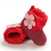 A pair of red fuzzy baby first walker shoes with pink floral accents.