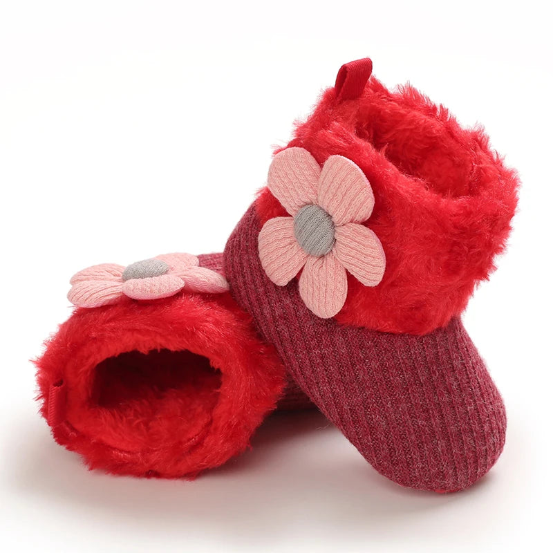 A pair of red fuzzy baby first walker shoes with pink floral accents.