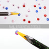 A close-up view of a black pen with a yellow tip, used to pick up nail rhinestones and other embellishments.