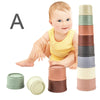 A baby is shown with a set of boat-shaped stacking cups in various colors like green, beige, and brown.