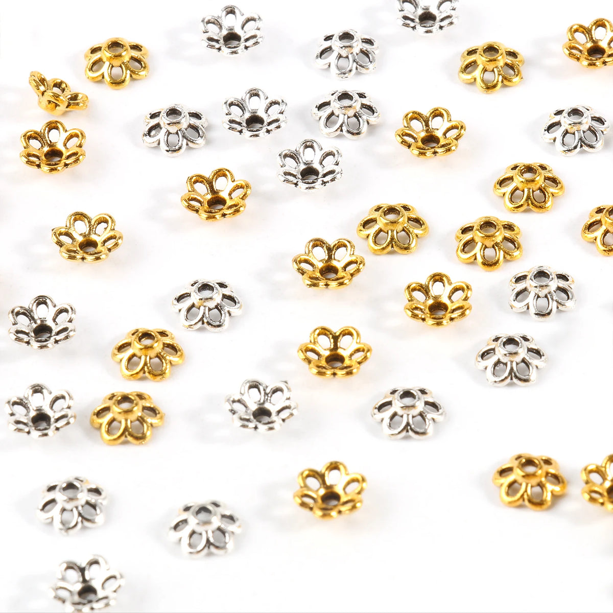 A collection of small, hollow flower bead caps in gold and silver finishes for jewelry making.