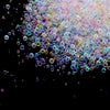 A close-up of iridescent, multi-colored glass bubble beads scattered against a black background.