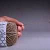 A hand holds a 200-foot organic hemp wick, which is lit and smoking.