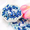 A bowl filled with assorted blue and white pearl beads for jewelry making.