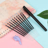 A set of black automatic fade pens with clear refills is displayed on pink and blue paper.