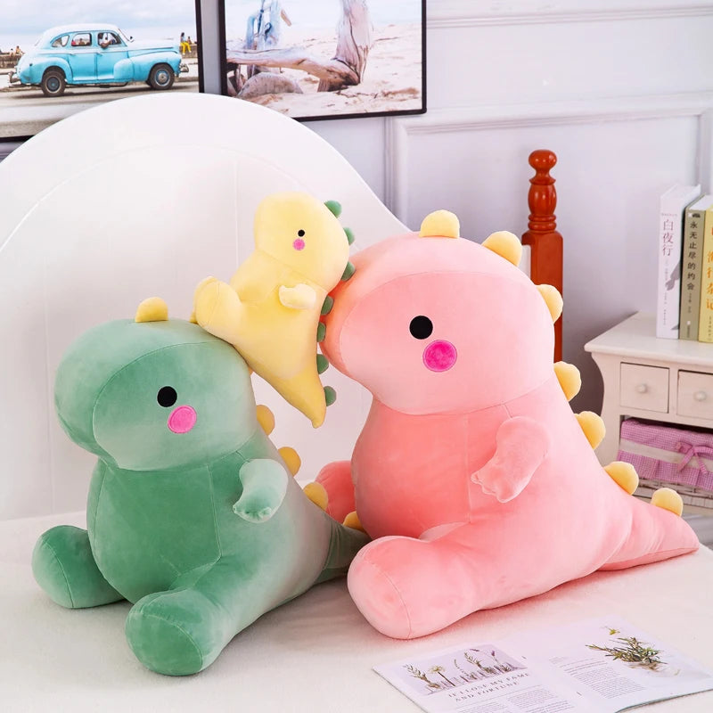 A pair of soft pink and green dinosaur plush toys sitting on a white surface.