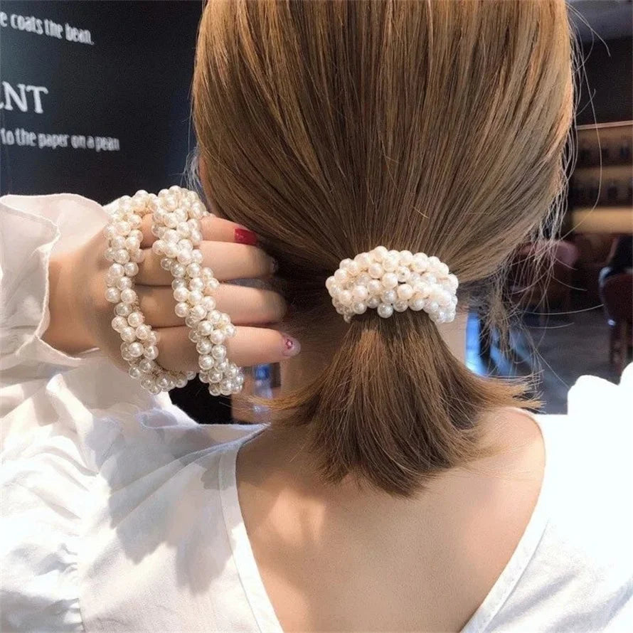 A woman's back shows elegant pearl hair ties styled into a ponytail with a bow scrunchie.