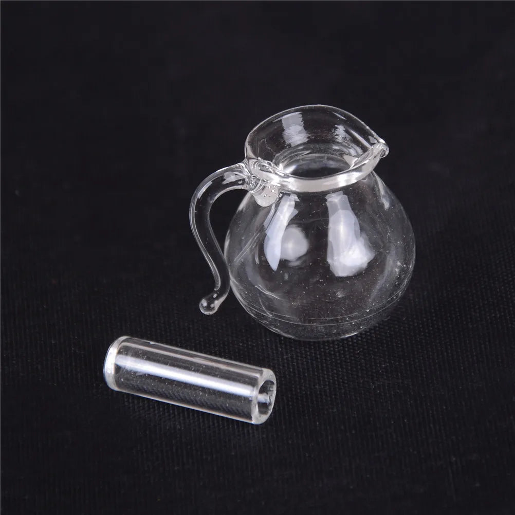 A clear glass miniature alloy kettle with a handle is shown next to a small cylindrical glass tube.