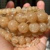 A collection of round, translucent amber-colored gemstone beads for jewelry making.