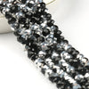 A close-up of black and silver faceted crystal glass beads strung together for jewelry making.