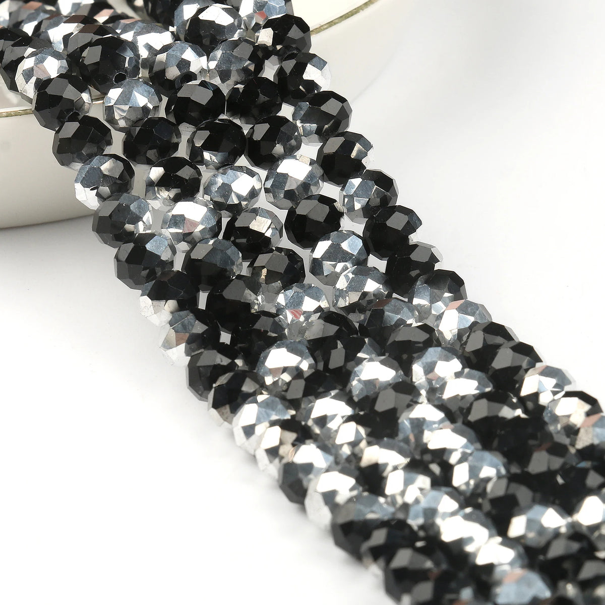 A close-up of black and silver faceted crystal glass beads strung together for jewelry making.