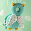 A light blue soft baby head protector pillow with yellow ears and white wings is shown against a pale green background.