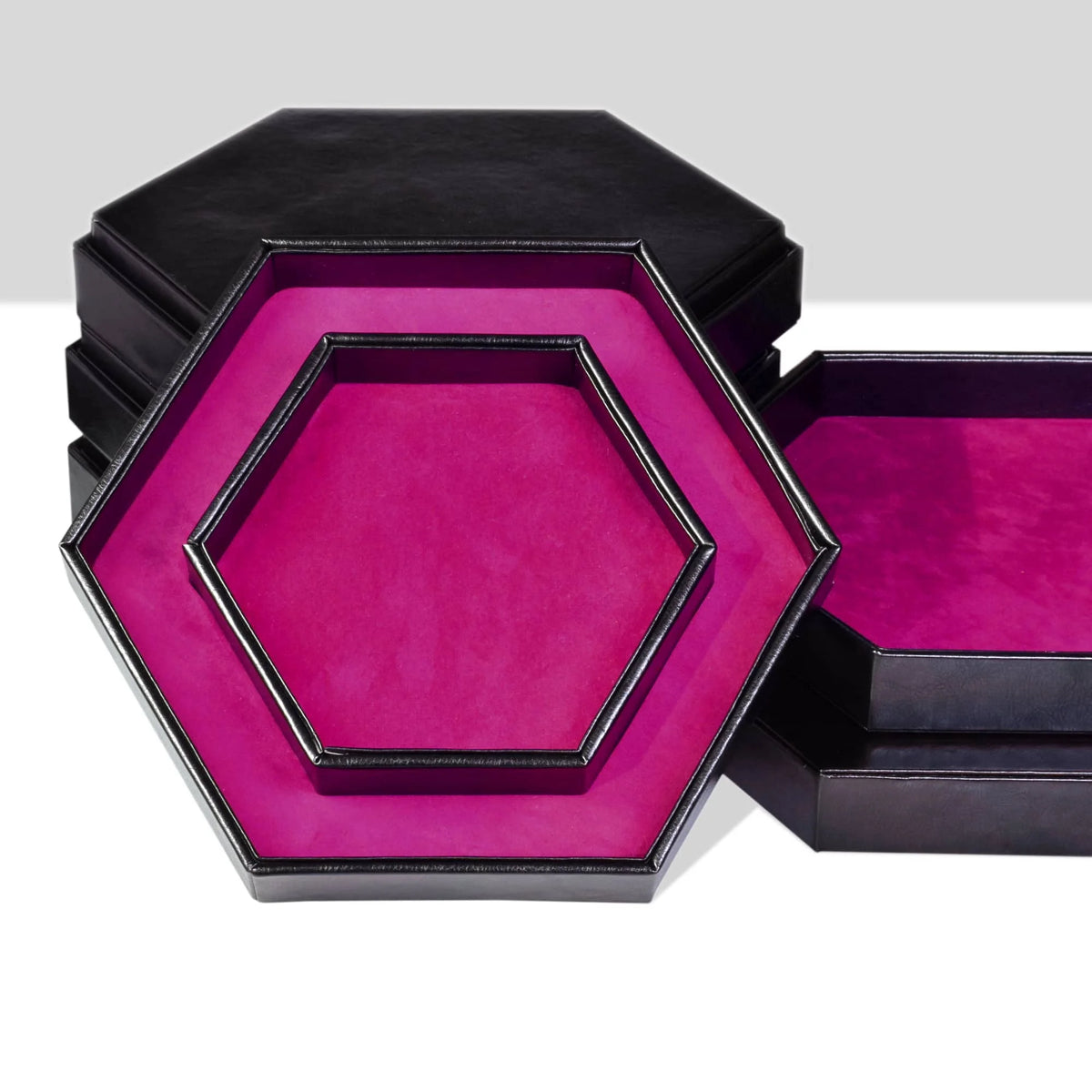 A black storage box with a hexagonal tray featuring a vibrant magenta velvet interior.