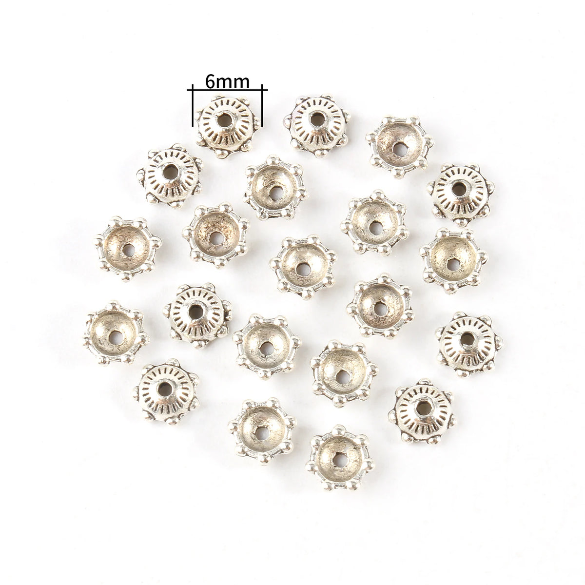 A collection of small, silver-toned Tibetan style hollow flower bead caps for jewelry making.