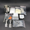 A complete candle making kit showing a metal pouring pot, various wicks and fixators in plastic bags, and wax pieces.