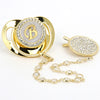 Gold and clear rhinestone pacifier featuring a personalized initial on a silicone disc with a clip.