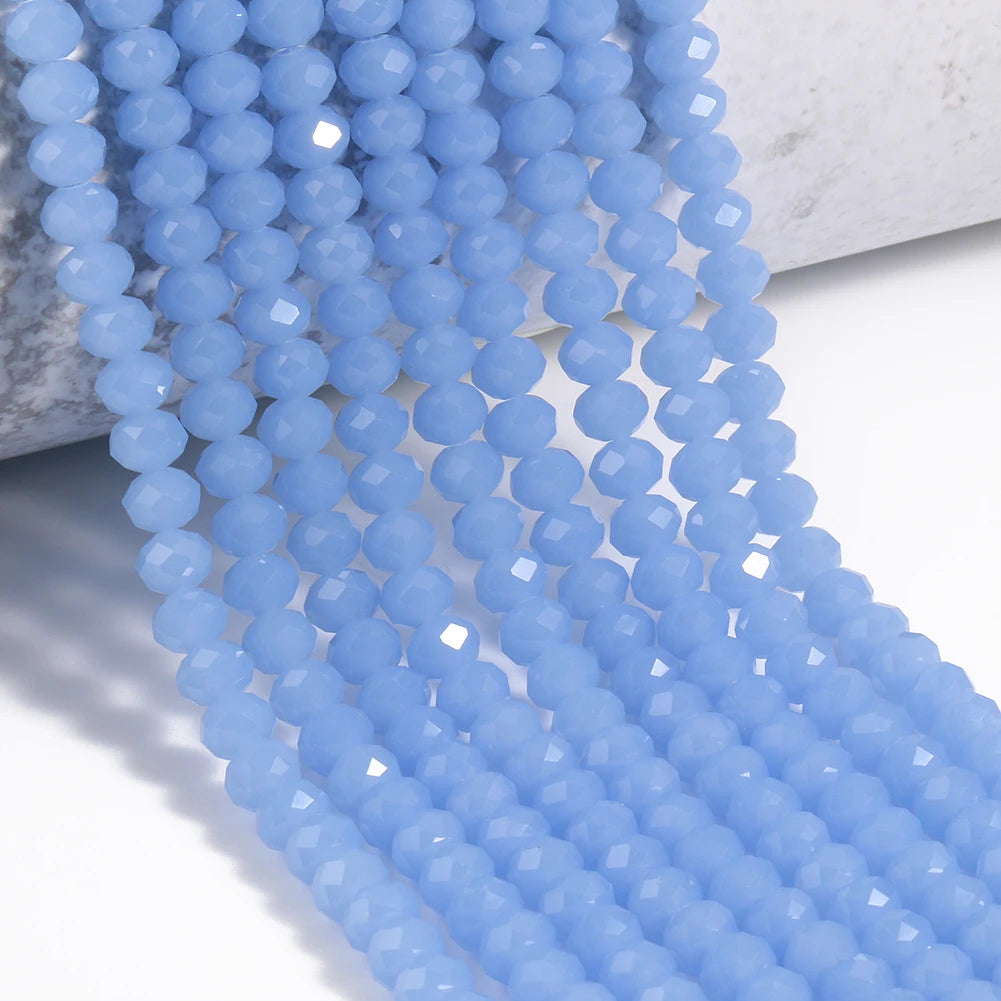 A strand of light blue faceted crystal glass beads draped over a white surface.