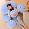A woman is relaxing while cuddling several blue and light blue plush toys shaped like anime slime characters.