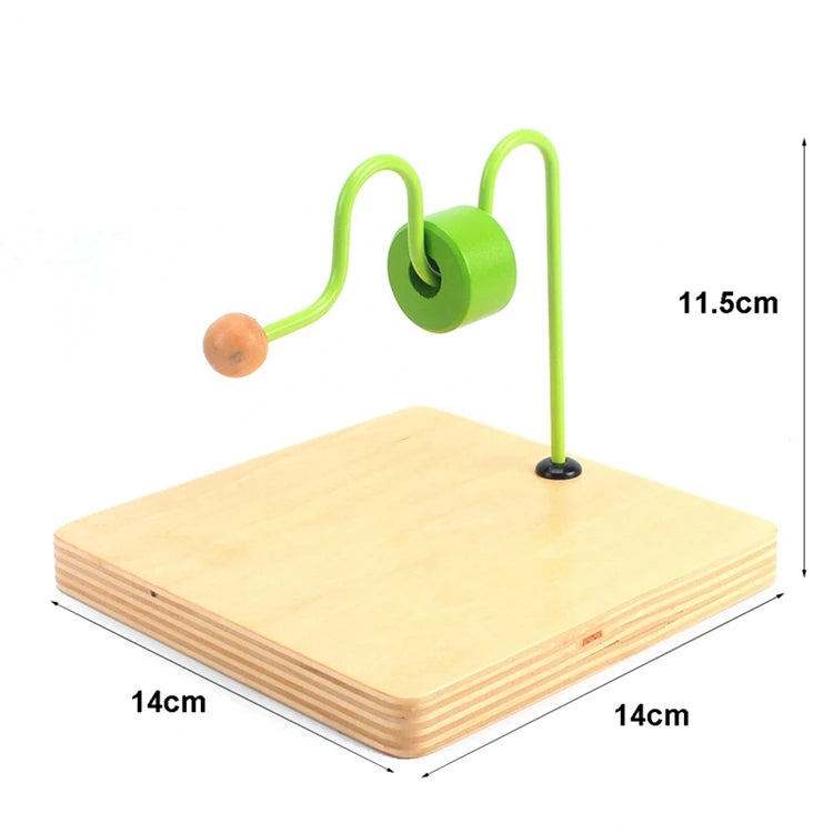 A green wooden sensory toy set with a handle and ball resting on a light wood board.