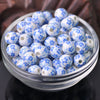 A clear glass bowl filled with small blue and white floral ceramic beads for jewelry making