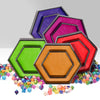 A stack of colorful hexagon-shaped dice trays and storage boxes in various shades of purple, pink, and green, with loose dice