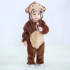 A baby wearing a brown animal hooded romper with a tan chest patch standing against a white background.