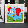A wooden jigsaw puzzle featuring an animated blue elephant with red ears and a yellow sun in a green field.