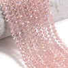 Pink faceted crystal glass beads strung together on a white surface.