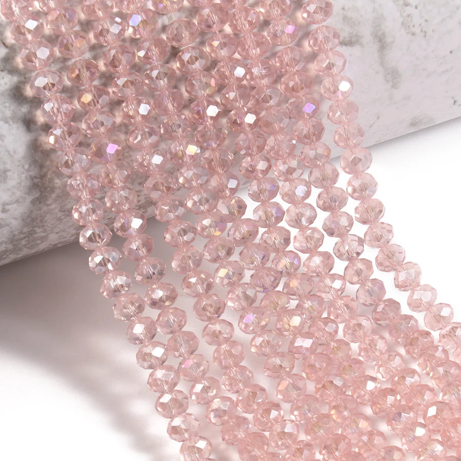 Pink faceted crystal glass beads strung together on a white surface.