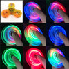 A collection of glow-in-the-dark LED fidget spinners demonstrating various colors and light effects.