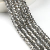 A close-up of silver-toned faceted crystal glass beads strung together for jewelry making.