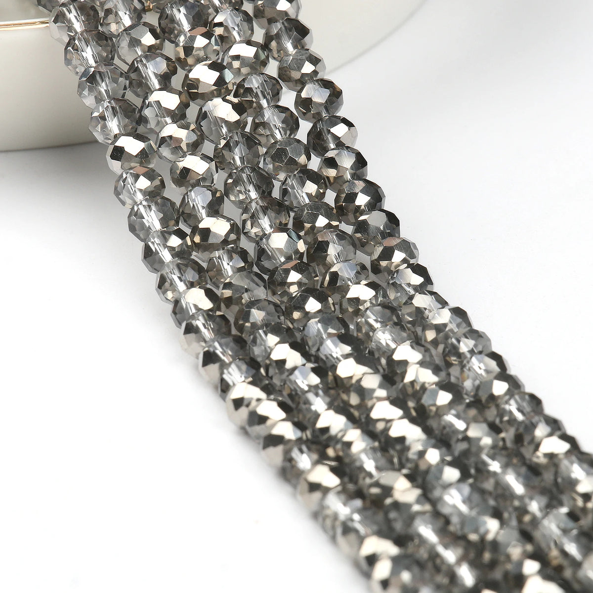 A close-up of silver-toned faceted crystal glass beads strung together for jewelry making.