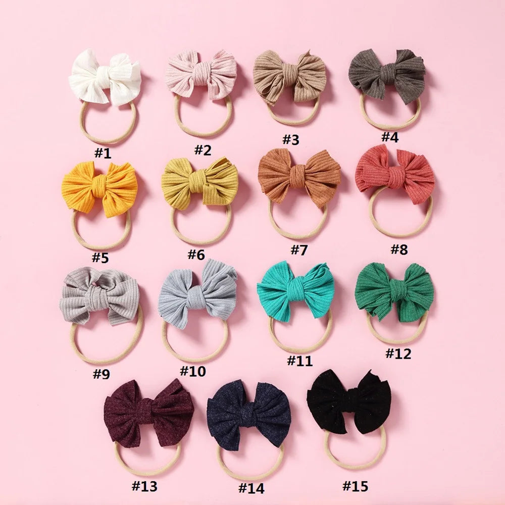 A collection of fifteen soft elastic hair bow headbands in various shades of beige, pink, brown, and green.