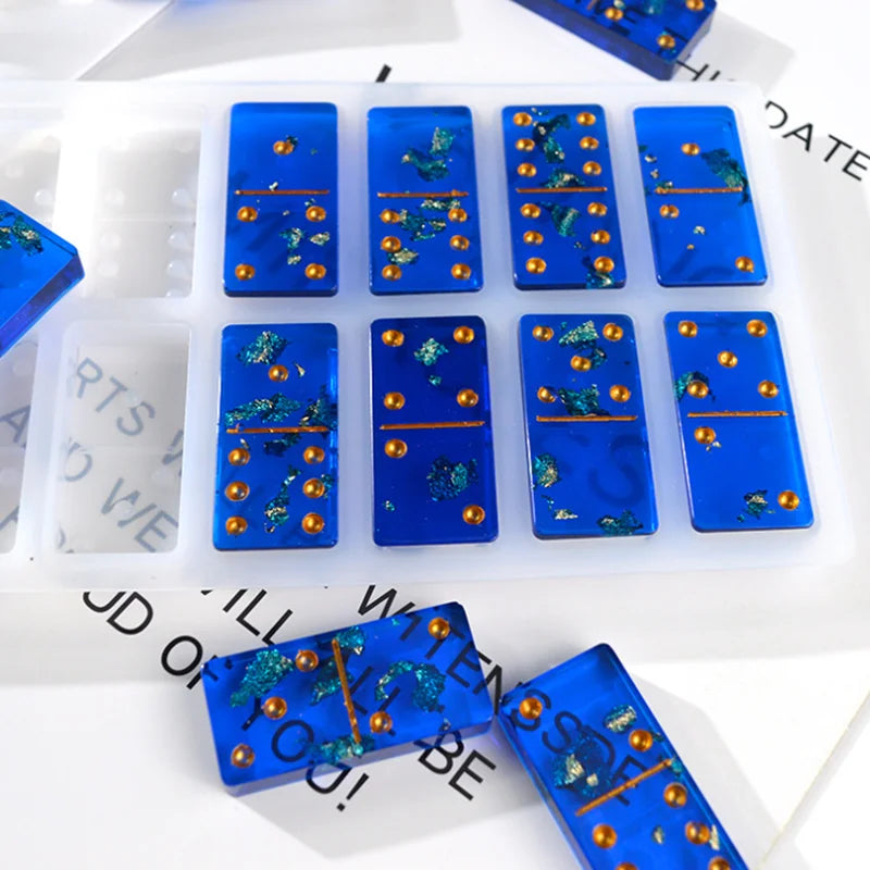 A silicone mold set for dominoes used in epoxy resin jewelry making featuring blue and gold colored pieces.