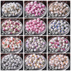 A grid of 12 glass bowls filled with various shades of floral ceramic beads for jewelry making