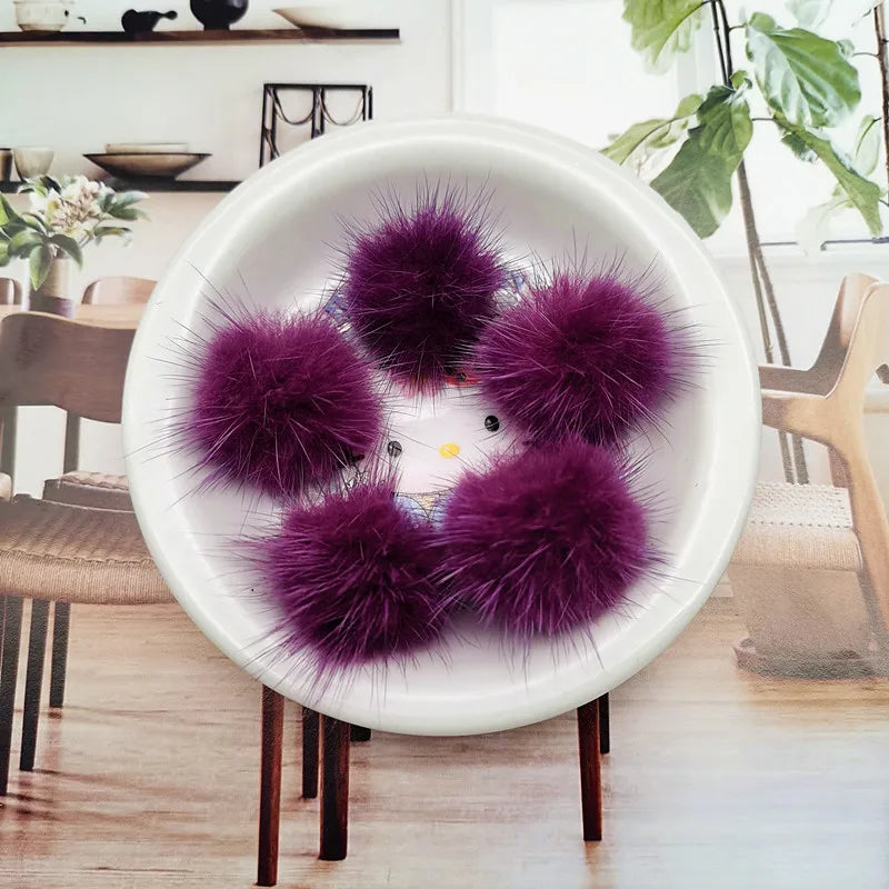 A white bowl filled with purple mink fur pom poms for crafts and accessories