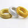Three strands of flexible aluminum craft wire in gold, silver, and yellow are laid out on a white surface.