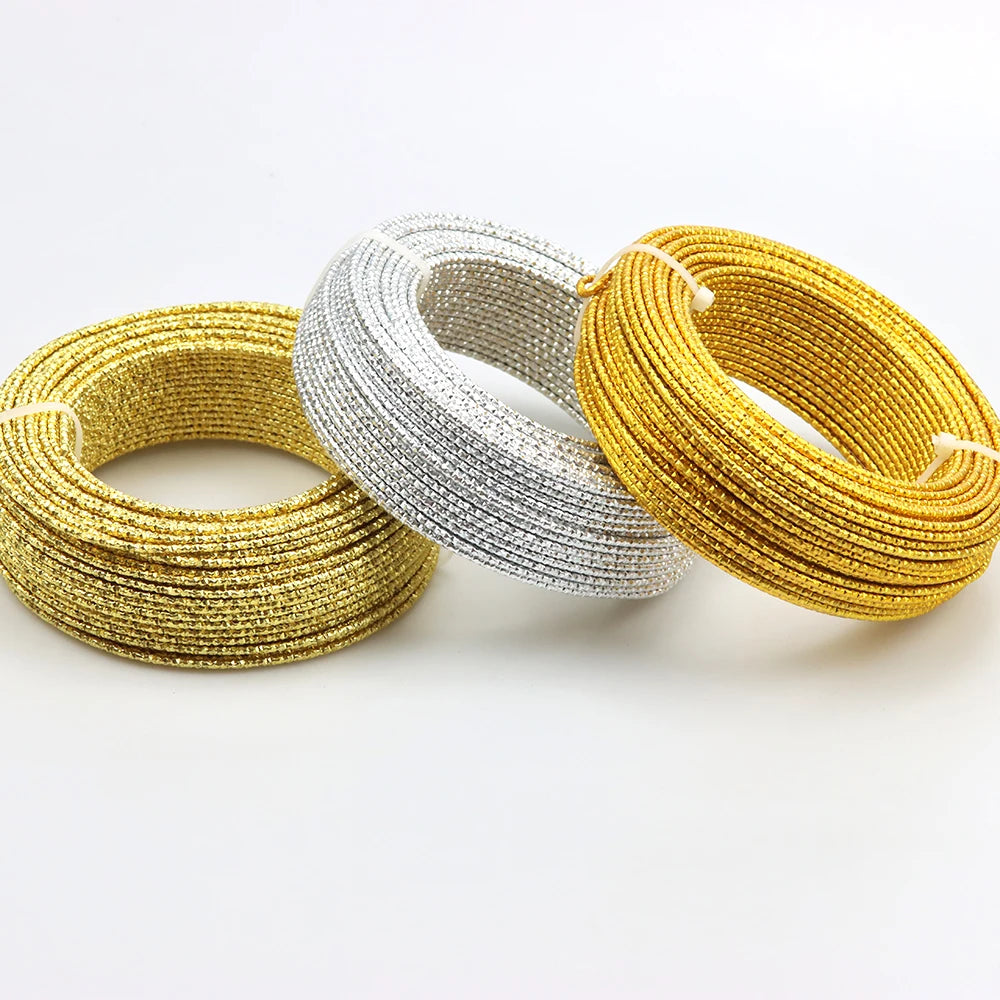 Three strands of flexible aluminum craft wire in gold, silver, and yellow are laid out on a white surface.