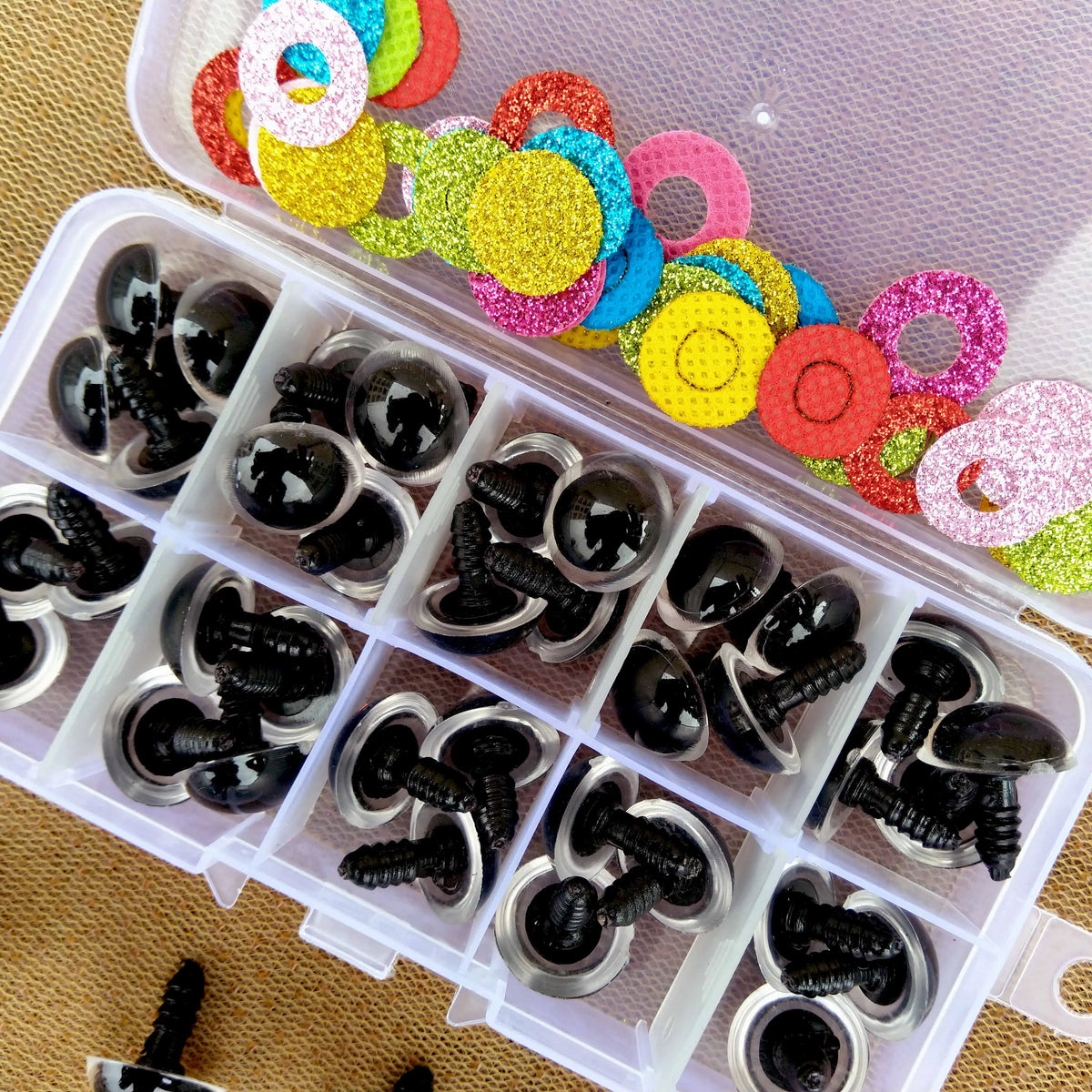 A clear plastic box filled with colorful plastic safety eyes for dolls and amigurumi