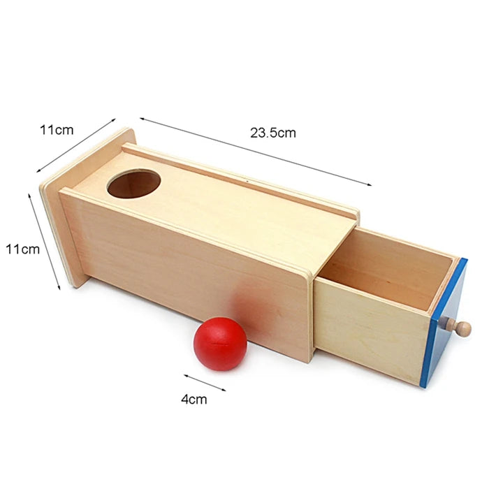 A wooden sensory toy set featuring a rectangular box with a hole and an attached tray, used for toddler play.