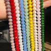 A hand holds multiple strands of faceted crystal glass beads in various colors including red, pink, white, blue, green, and y