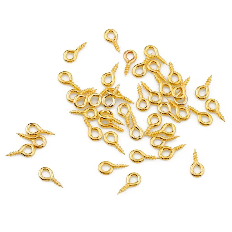 A collection of small gold-colored eye pins with screw threads for jewelry making.
