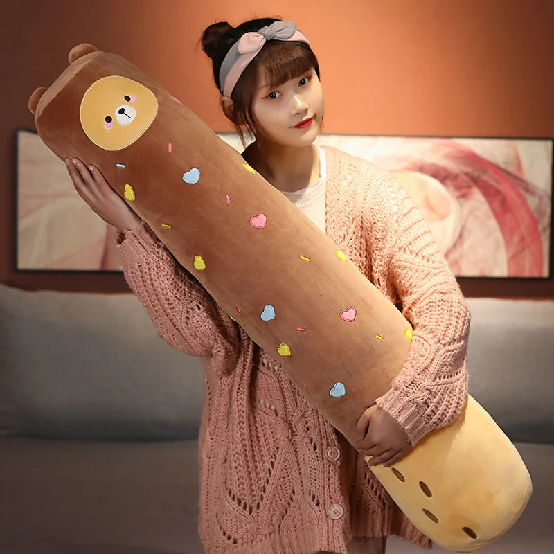 A woman holds a long, brown stuffed animal plush pillow with yellow accents and colorful confetti dots.