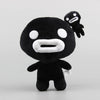 A black collectible plush toy resembling a stylized, round creature with white features and an appendage.