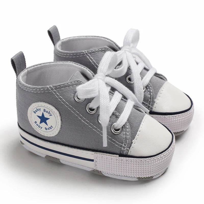 Gray canvas baby shoes with white laces and a star detail shown from the top view